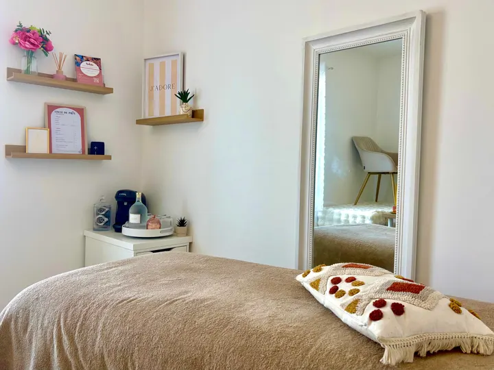Cabine d’épilation de l’Institut Solaïa au Landreau : table de soin, grand miroir et étagères fleuries