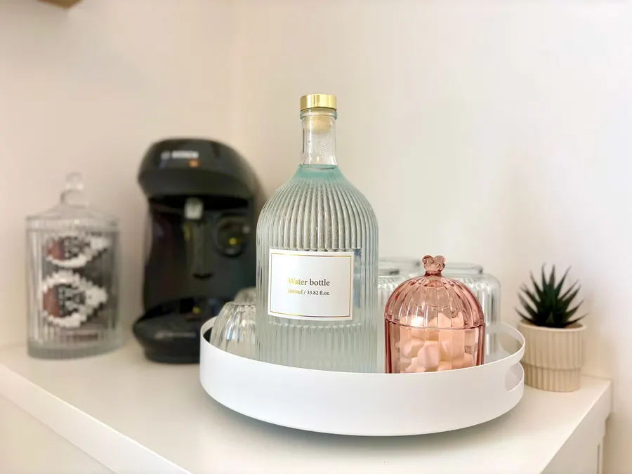 Coin accueil de l’Institut Solaïa : carafe d’eau, machine à café et bonbonnière rose sur un plateau blanc