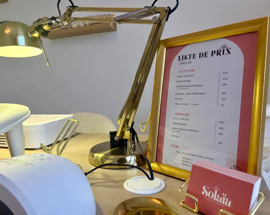Liste de prix des ongles encadrée et cartes de visite Solaïa posées sur la table de manucure