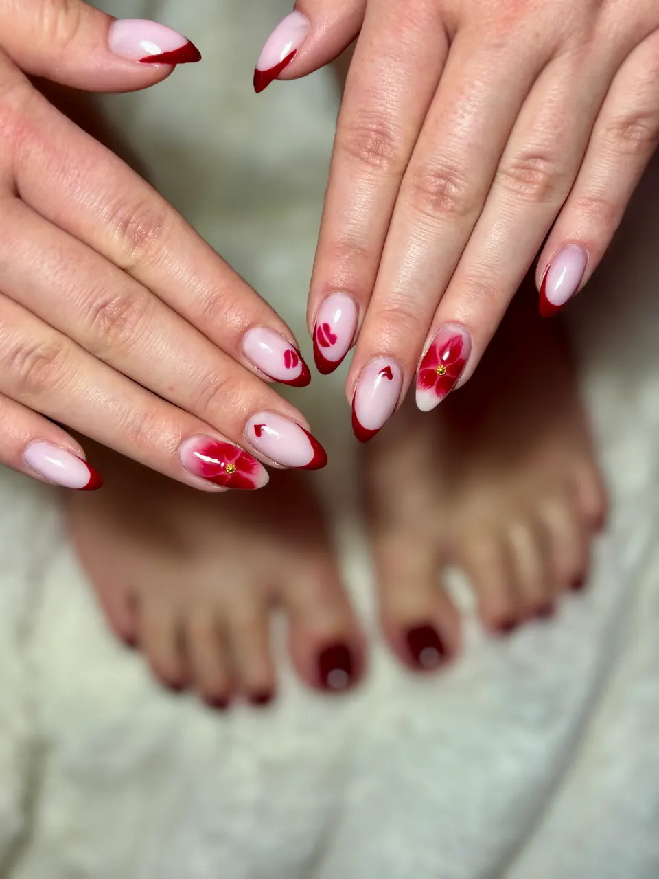 Manucure french rouge à motifs floraux assortie à une beauté des pieds bordeaux