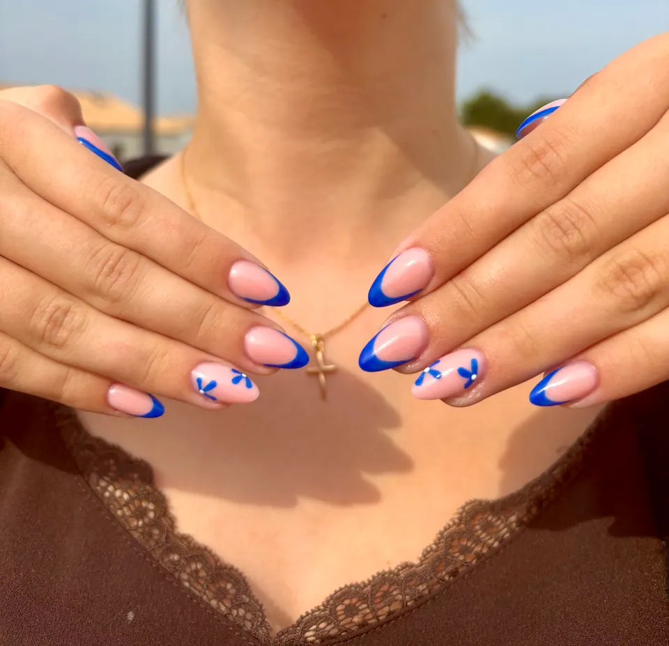 Ongles amande courts à french bleu roi, avec de petites fleurs bleues peintes