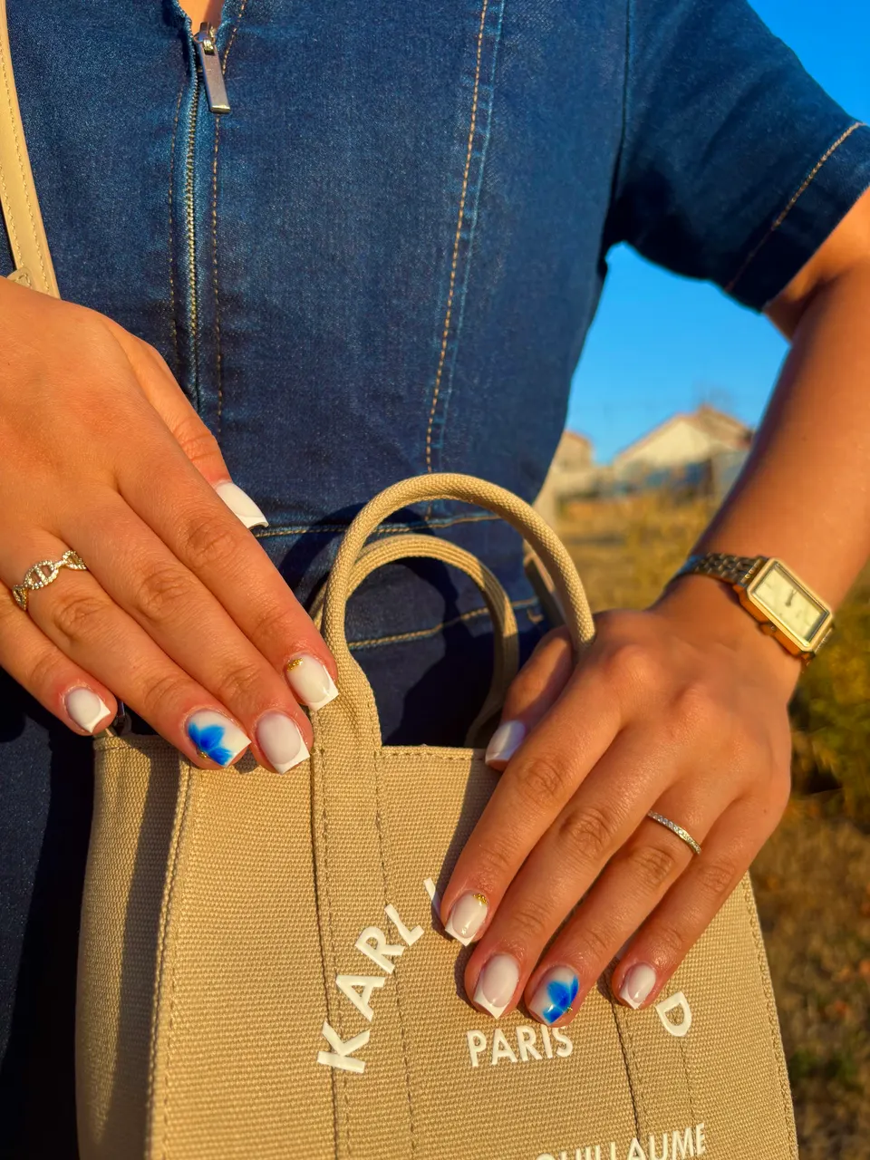 Ongles carrés courts à french blanche, avec une fleur bleue aquarelle et du caviar doré