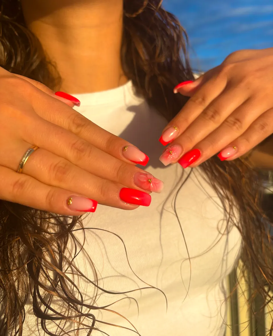 Ongles carrés à french rouge corail avec une fleur blanche en relief et caviar doré